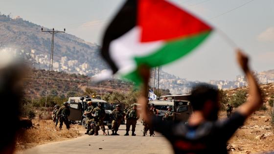 A Palestinian protester facing Israeli security forces, waves a national flag during a demonstration against the establishment of Israeli outposts on their lands, in Beit Dajan, east of Nablus in the Israeli-occupied West Bank, on October 22, 2021. (Photo by ABBAS MOMANI / AFP)
